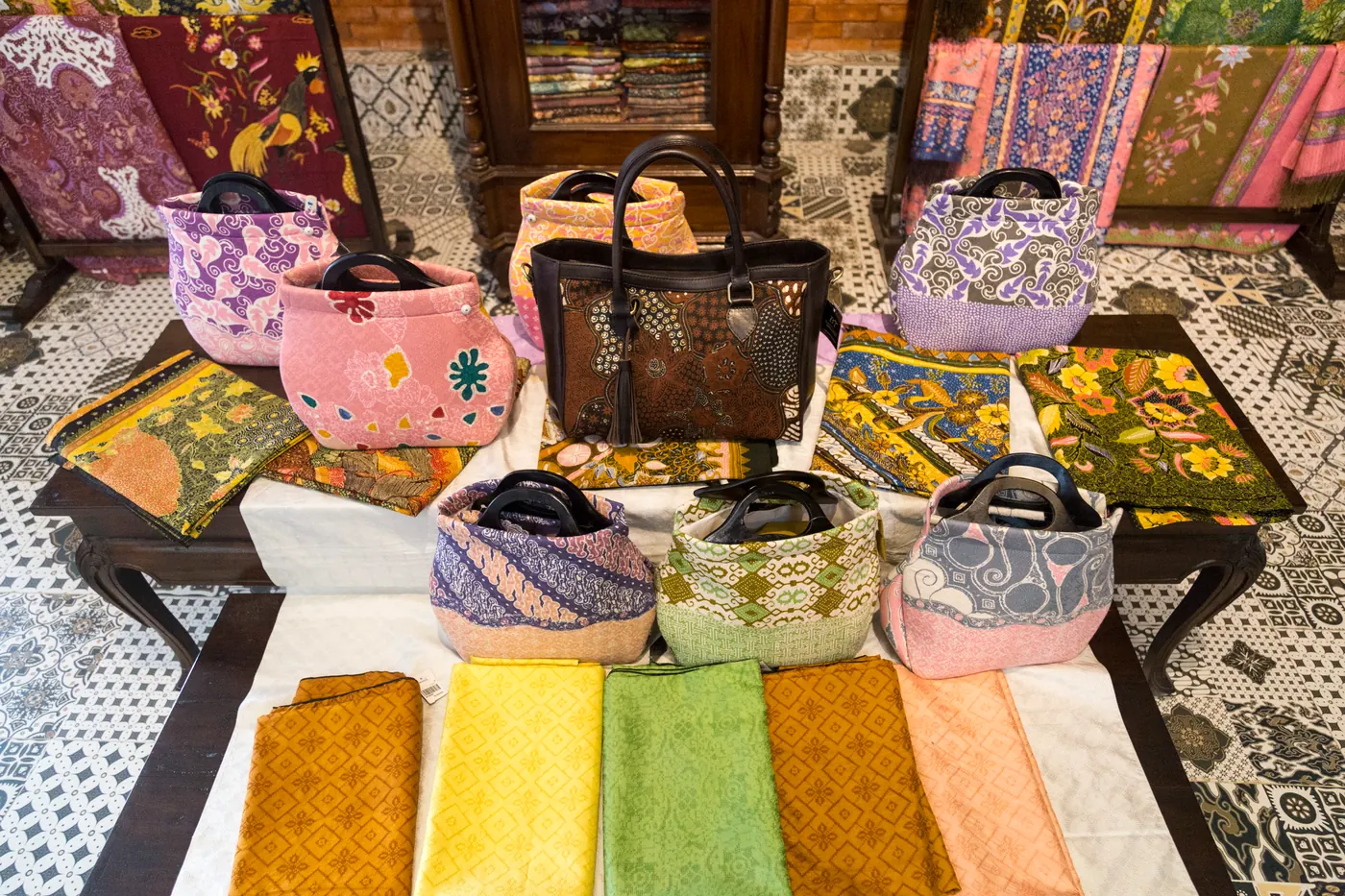 Tumpukan kain batik dan tas berbahan batik yang sudah jadi, tertata siap dijual di sebuah gerai