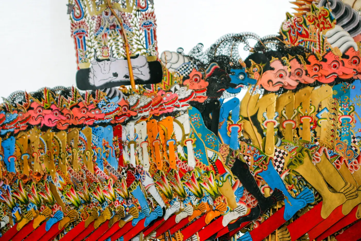 Puluhan tokoh wayang kulit yang sudah selesai ditatah dan diwarnai, tersusun berjajar rapat dengan gunungan di bagian belakang
