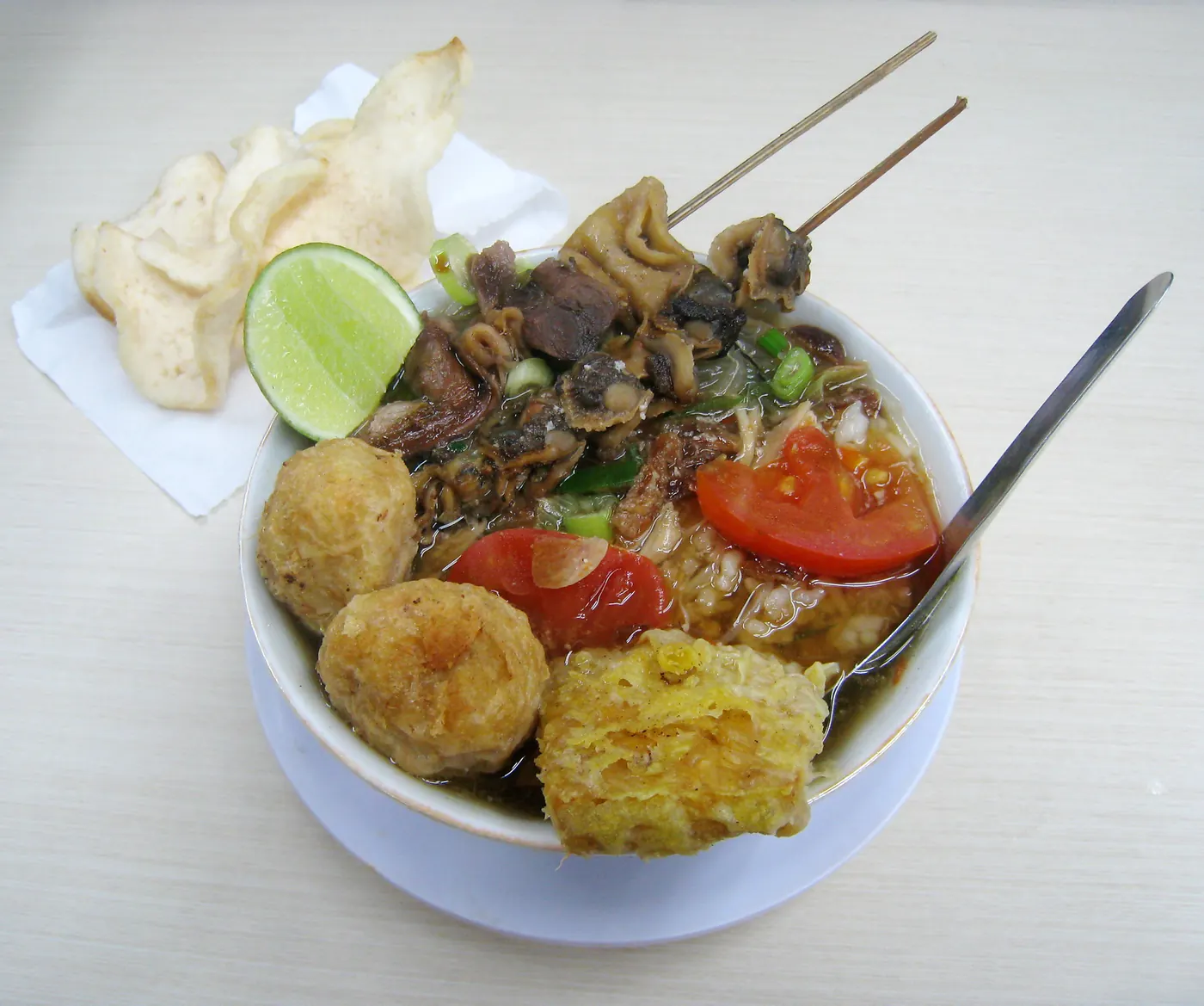 Semangkuk soto ayam khas Semarang dengan tomat, perkedel, sate jeroan, dan kerupuk. Foto: Wikimedia Commons, CC BY-SA 3.0