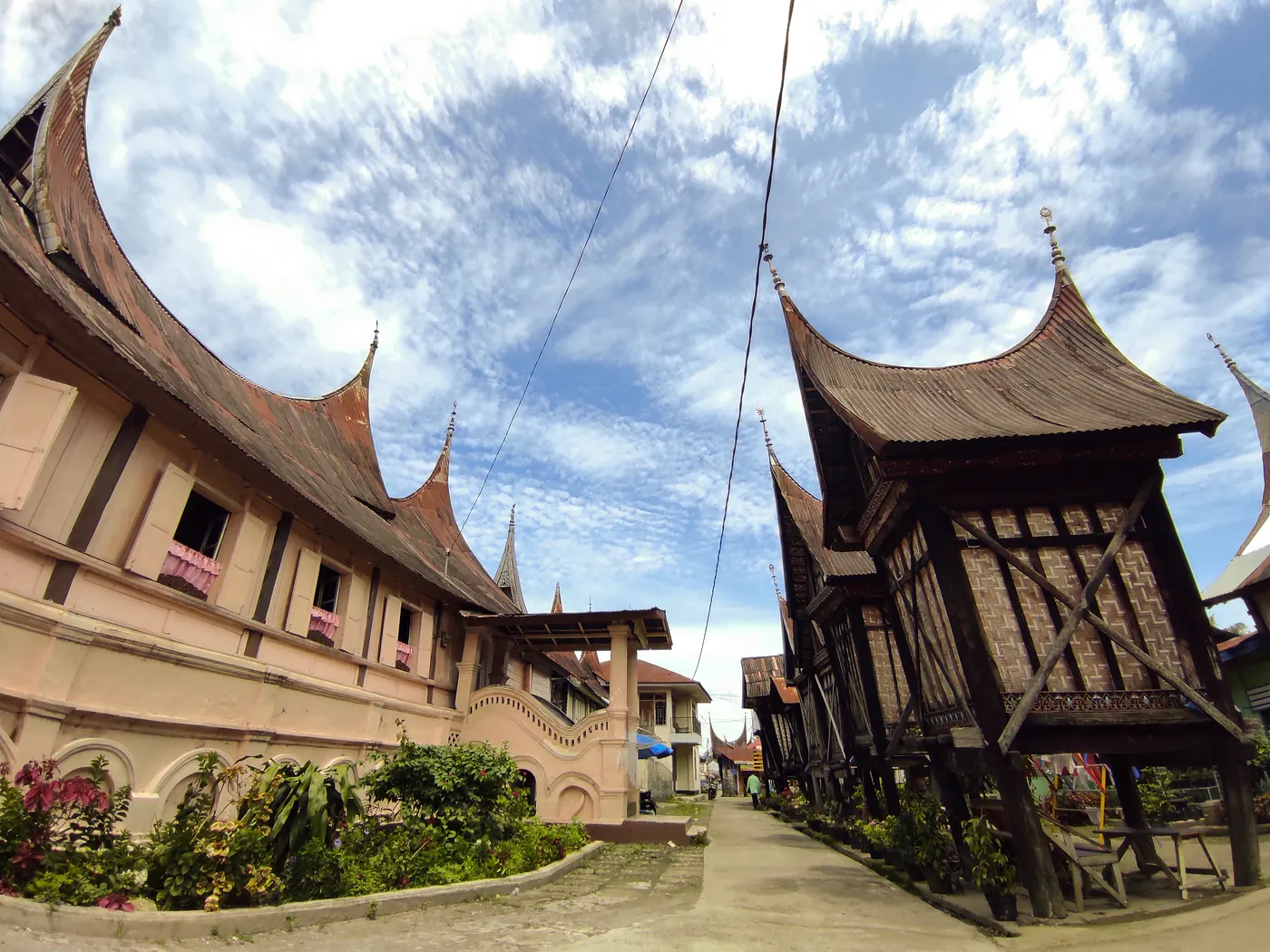 Rumah gadang dengan rangkiang atau lumbung padi beratap gonjong berdiri di halaman depannya
